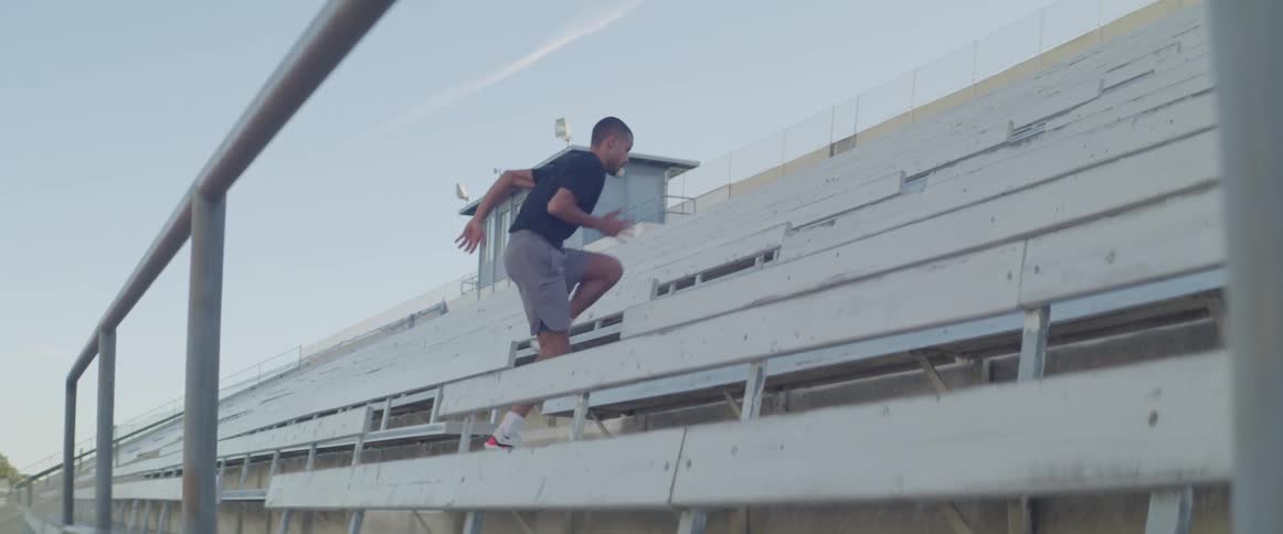 A young athletic male exercises by running up the steps of spectator stands
