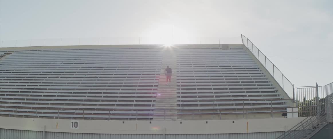 A man runs up the steps of an empty bleacher