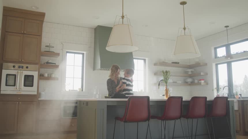 Mother tickles young son sitting on kitchen countertop