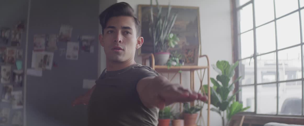Male holding a yoga pose indoors near window