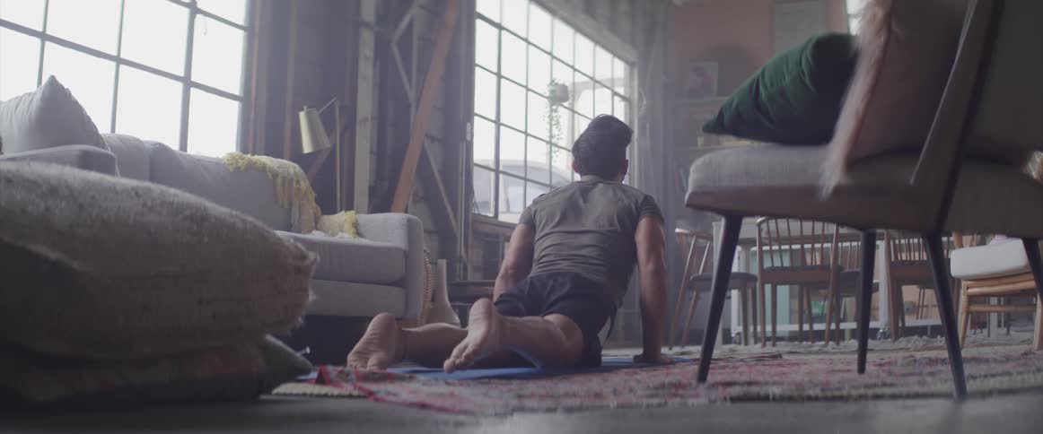 Man does v push ups on an exercise mat in the living room