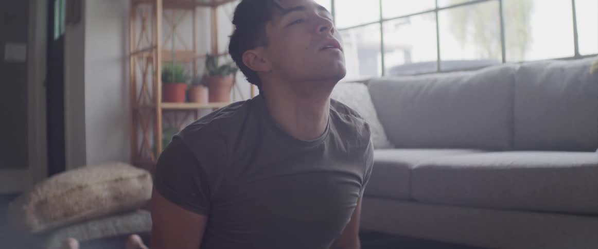 Man performs yoga in living room near large window