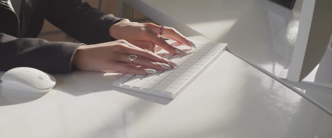 A woman is typing on a computer while sitting at a desk