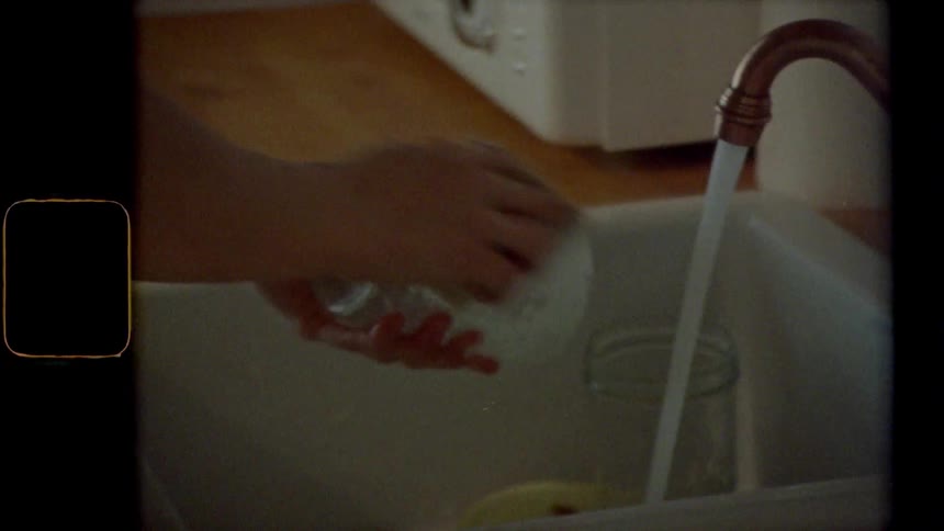 Vintage footage of a woman washing dishes at home