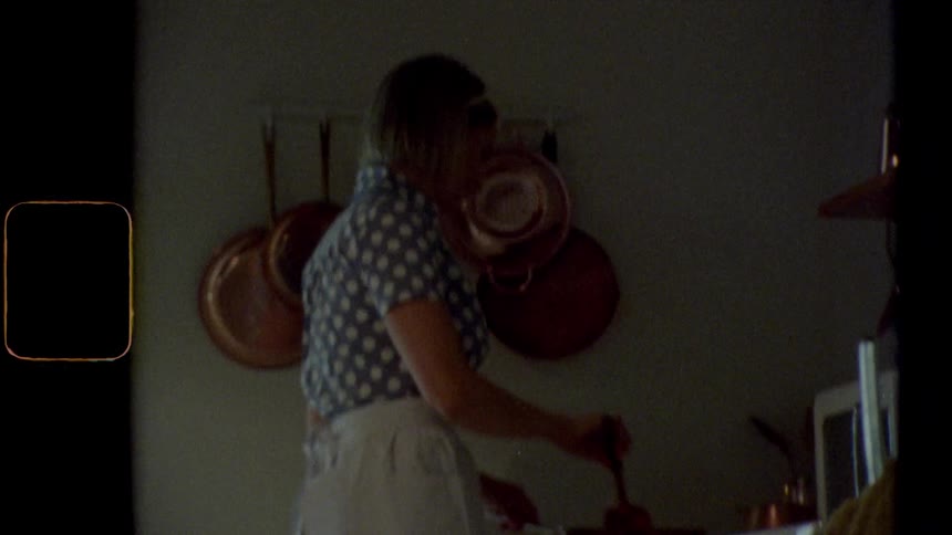 A woman stands in front of the stove cooking