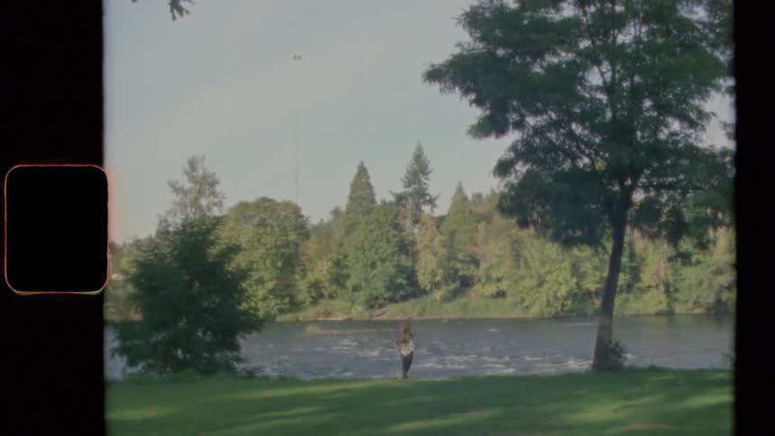 Woman stands on river bank as flowing river forms white water