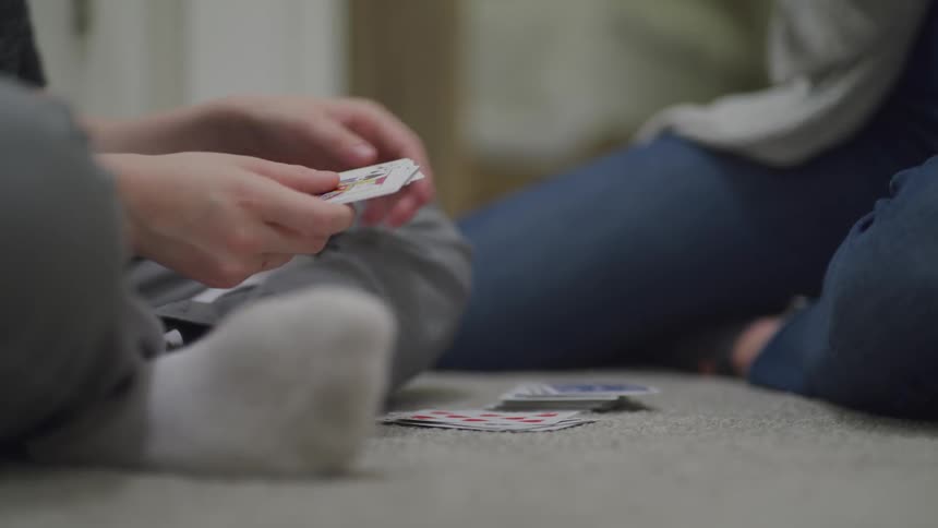 Two people sit playing cards