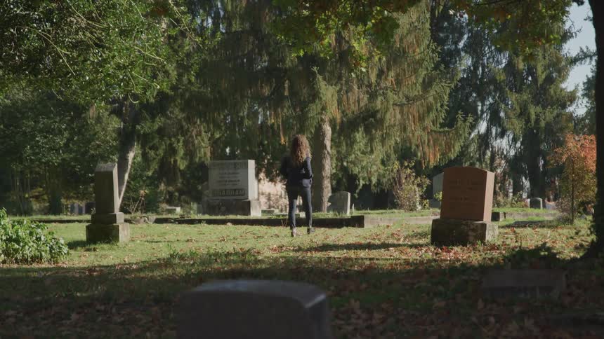 A woman walks through a cemetery