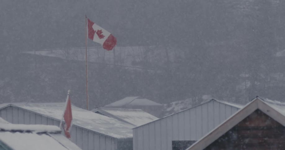 Heavy snow falls over the Canadian flag and the buildings
