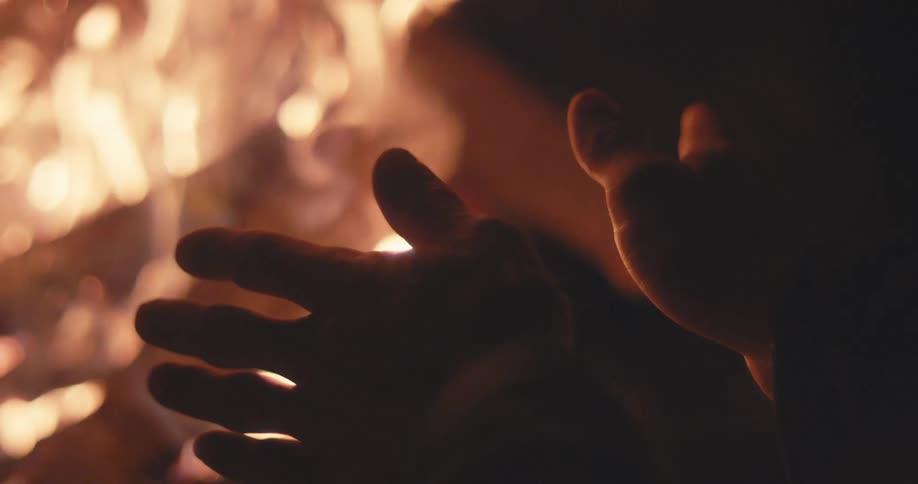 A person warming their hands near an open fire