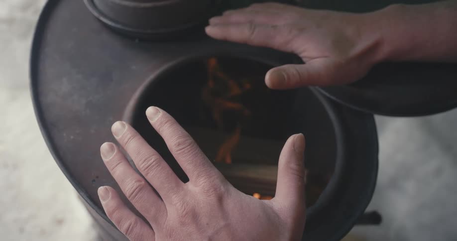 A man holding his hands over a wood burning stove