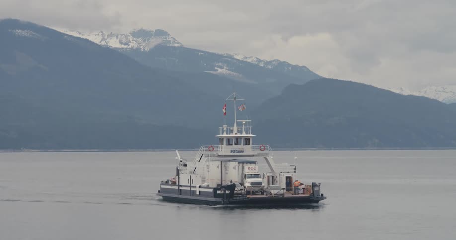 A ferry carries vehicles across a mountain lake