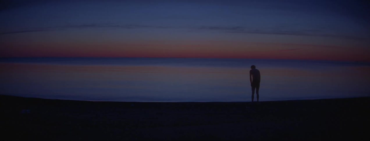 Man throws something into the ocean water while standing on the beach