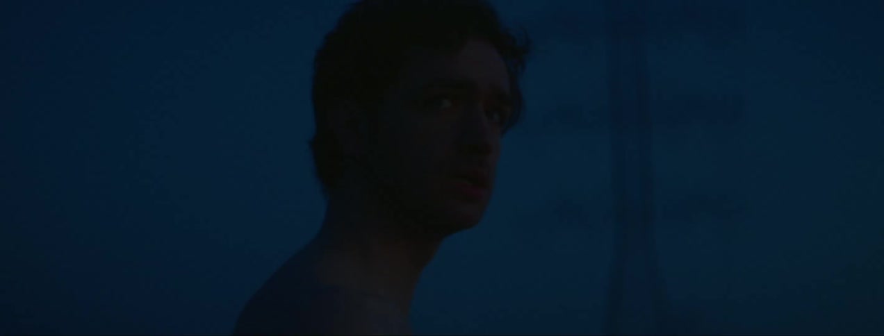 A man looks around nervously at sunset