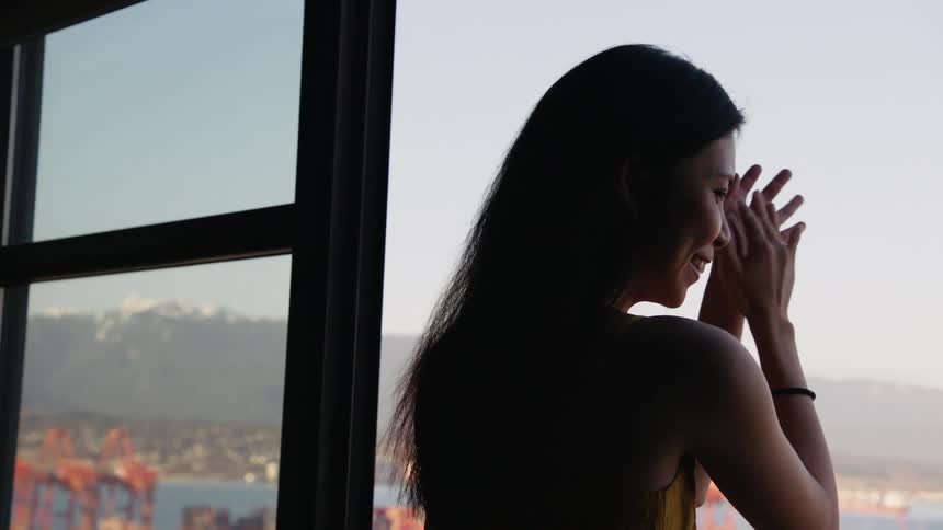 A woman on a balcony clapping and smiling