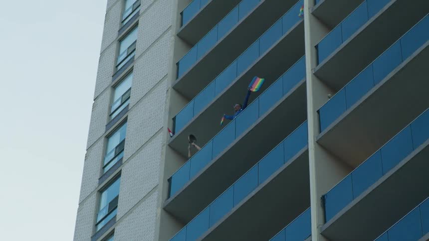 A man waves flags out his balcony window