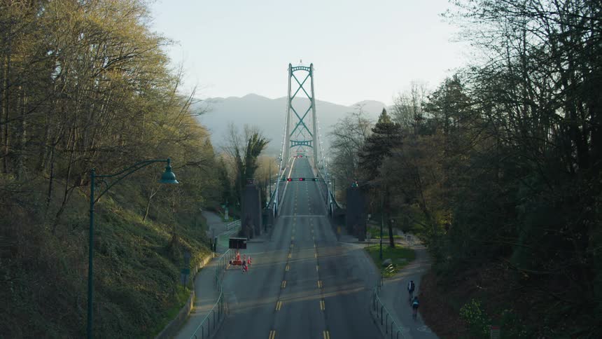 Two people cycle alongside a bridge