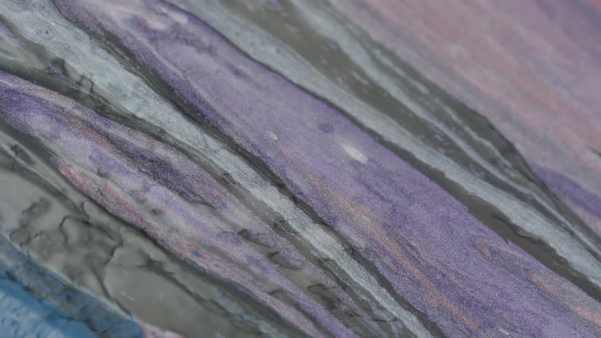 Colorful ink and paint liquid flowing in streaks over a marble surface