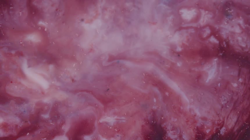Red and white liquids combine to form a marbled pink shade
