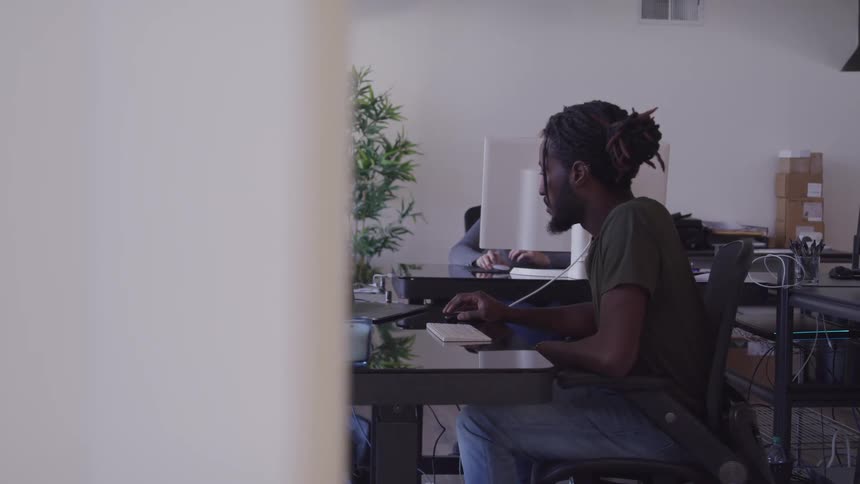 A man sits at an office computer desk
