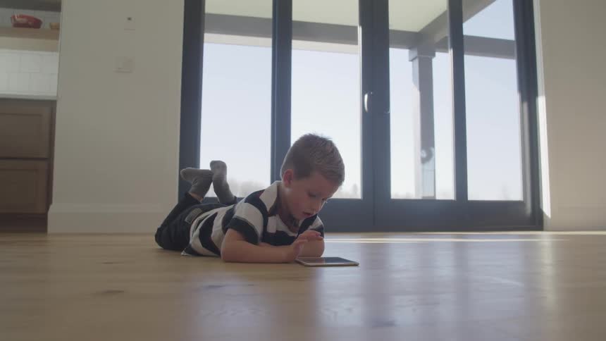 A boy is using a tablet on the floor