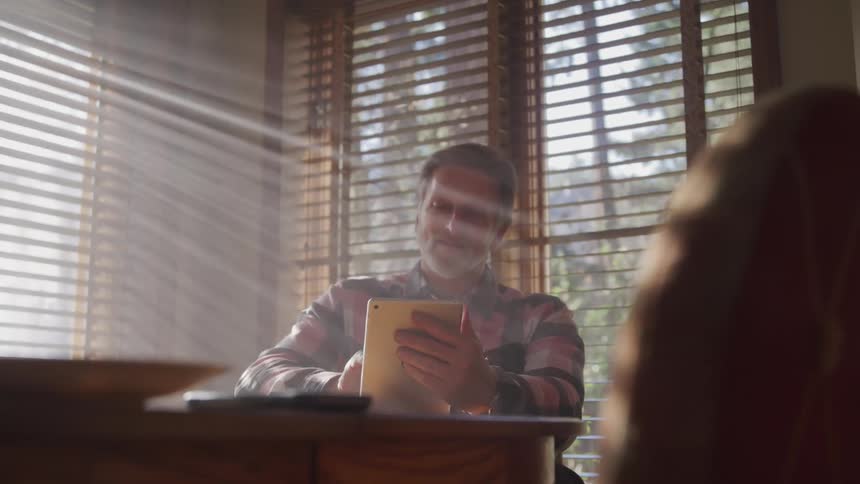 Man sitting at table using tablet and smiling