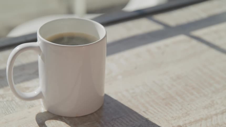 A steaming mug of hot coffee on a wood table