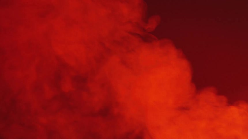 Orange colored vapor drifts and rises against red background