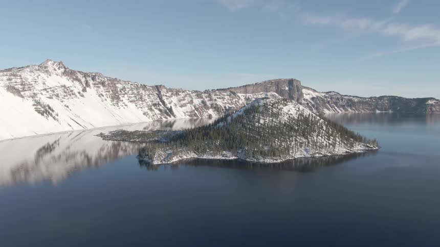 Island in the bay of a lake on the snow covered mountains at sunset