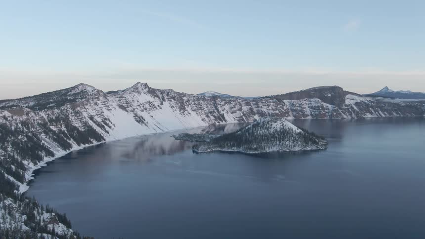 Island in the bay of a lake on the snow covered mountains at sunset