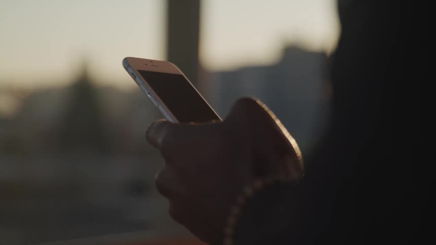 Persons hands use smartphone at sunset