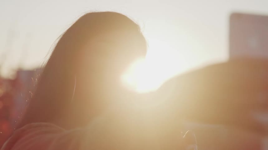 A woman is taking a selfie at sunrise