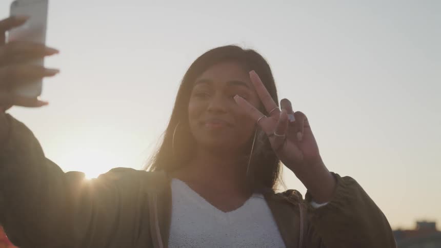 A teenage girl poses and takes a selfie on her cell phone