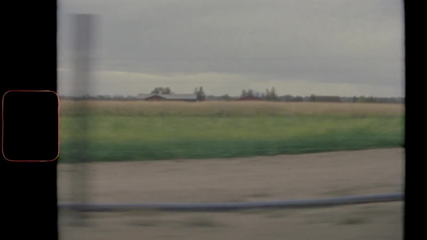Film footage from moving vehicle of rural area with farm