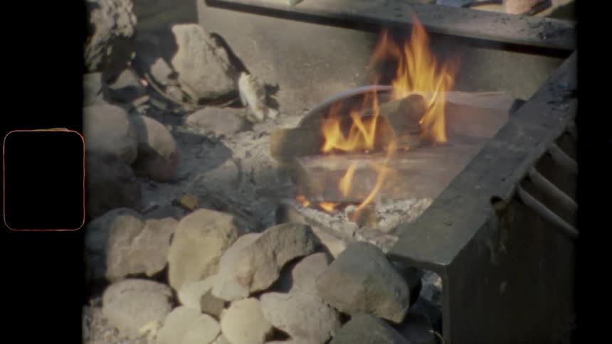 Vintage footage of a fire burning in a fire pit outdoors