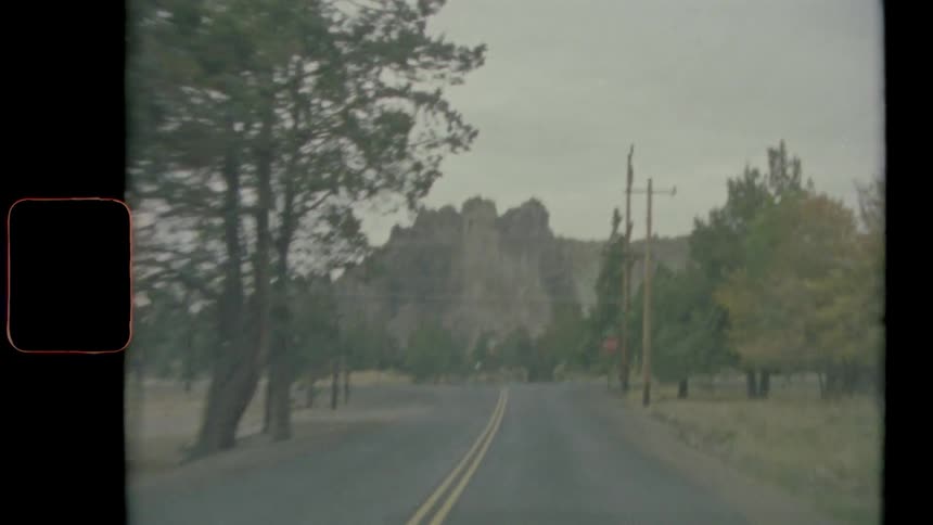 A rural tree lined road leads to a canyon