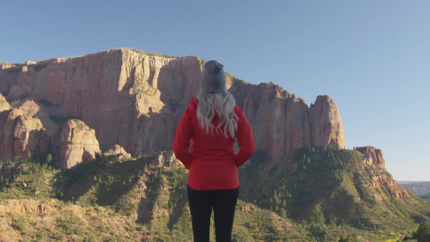 A woman is hiking outdoors near a cliff