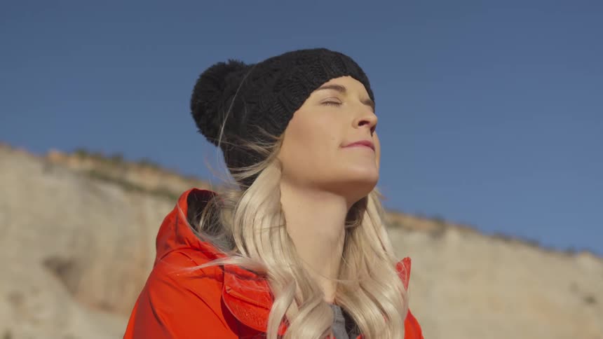 A woman is standing outside on a windy day