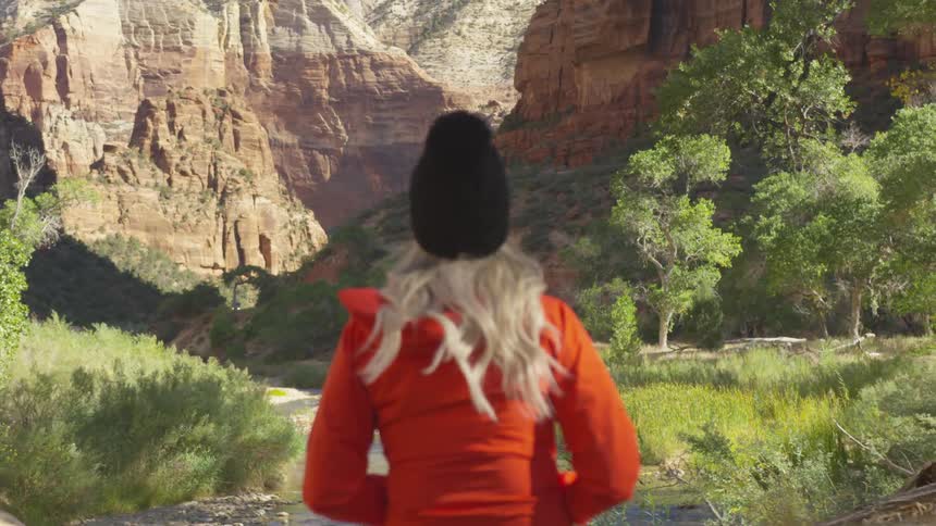 Woman sits overlooking hiking trail through ravine
