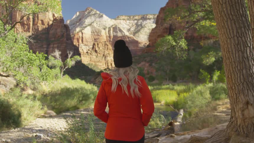 A woman walking below a canyon
