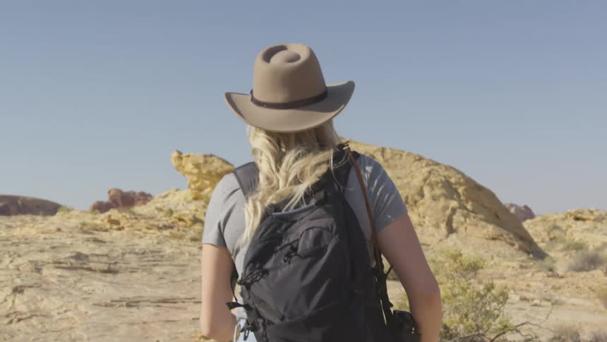 A young woman hikes up a rocky hill