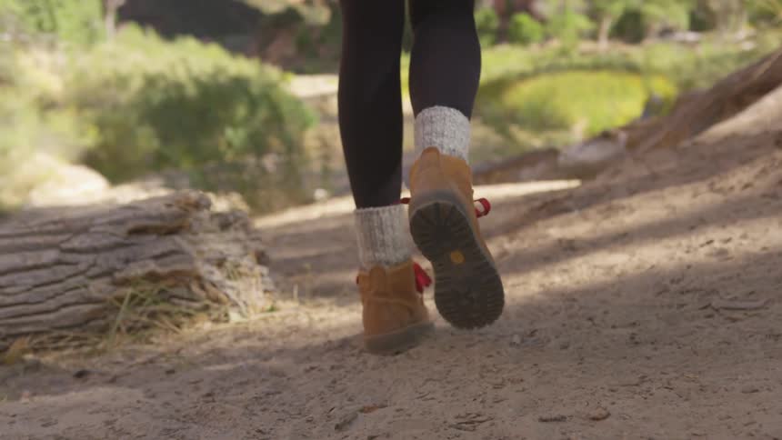 Close up of a womans boots while walking on a dusty trail in a canyon