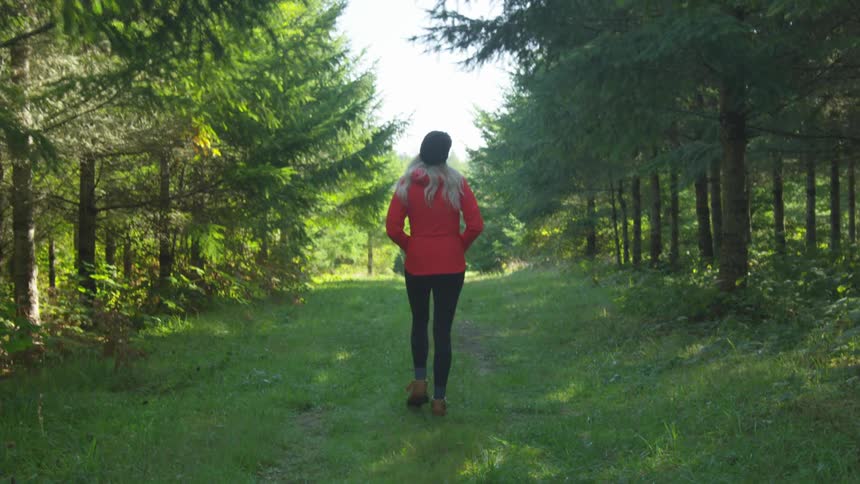 A woman is walking outdoors in a wooded area