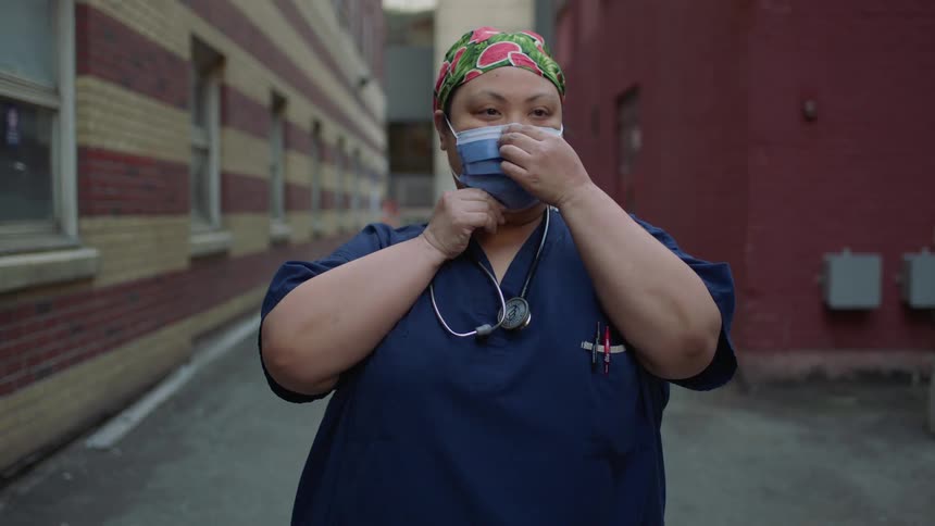 A nurse puts on a face mask