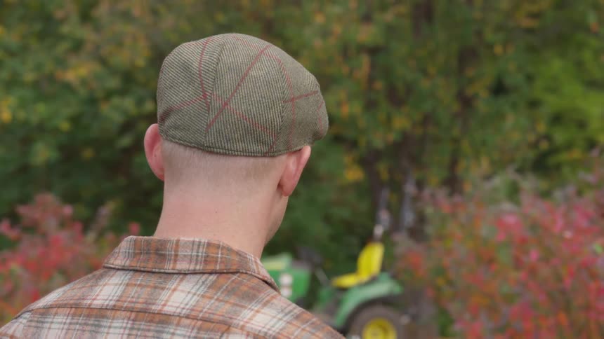 A man is standing outdoors next to a lawn mower