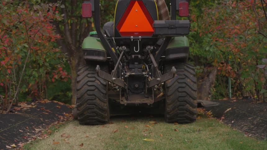 A motorized lawn mover driving over the grass in a garden