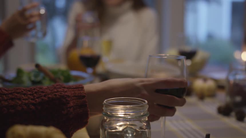 A person reaches for their wine glass on a dinner table