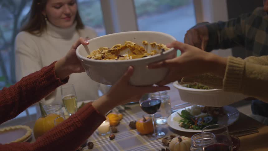 Family at thanksgiving table with turkey passing dishes