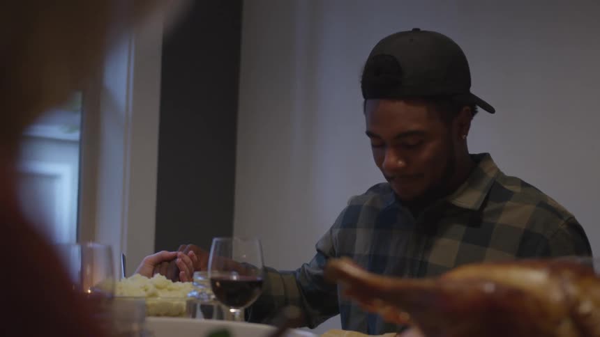 A man lowers his head a dinner table in prayer