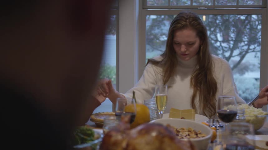 Family saying grace over thanksgiving dinner